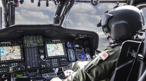 a man is sitting in the cockpit of a military helicopter.